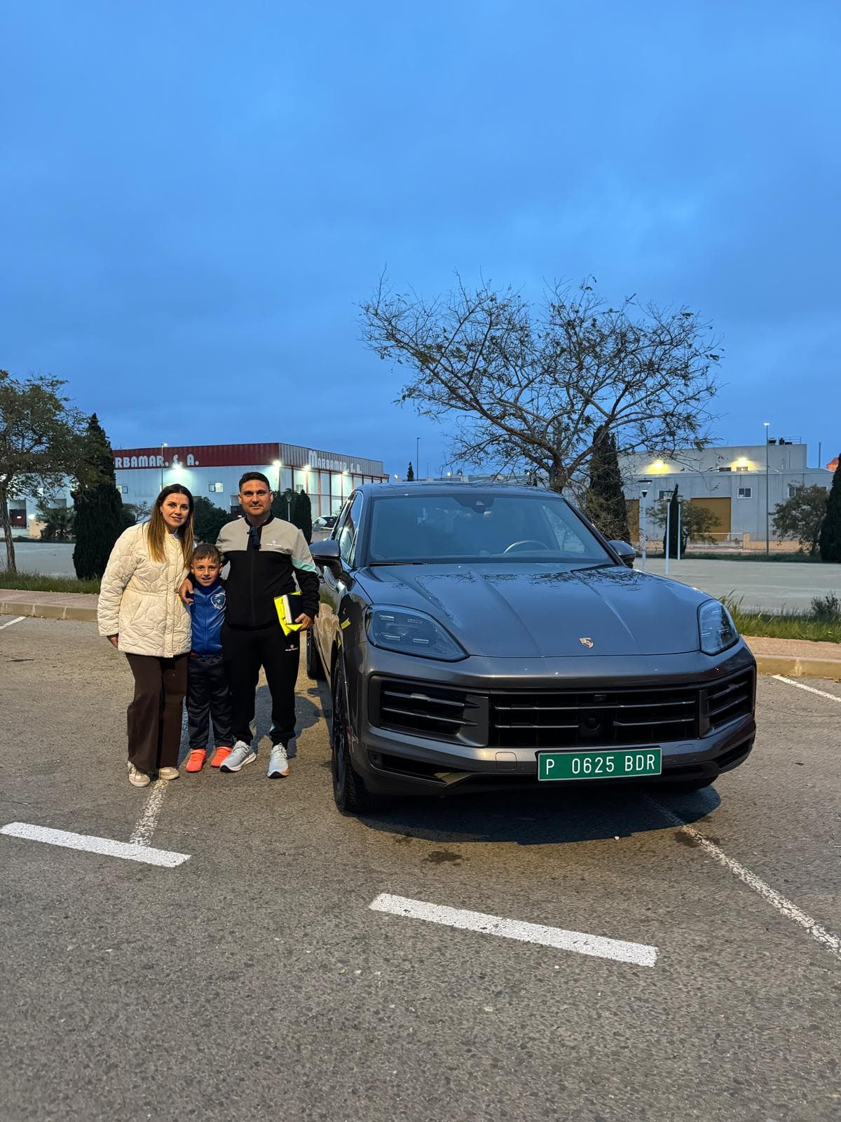 Tres personas junto a un Porsche durante una entrega documentada