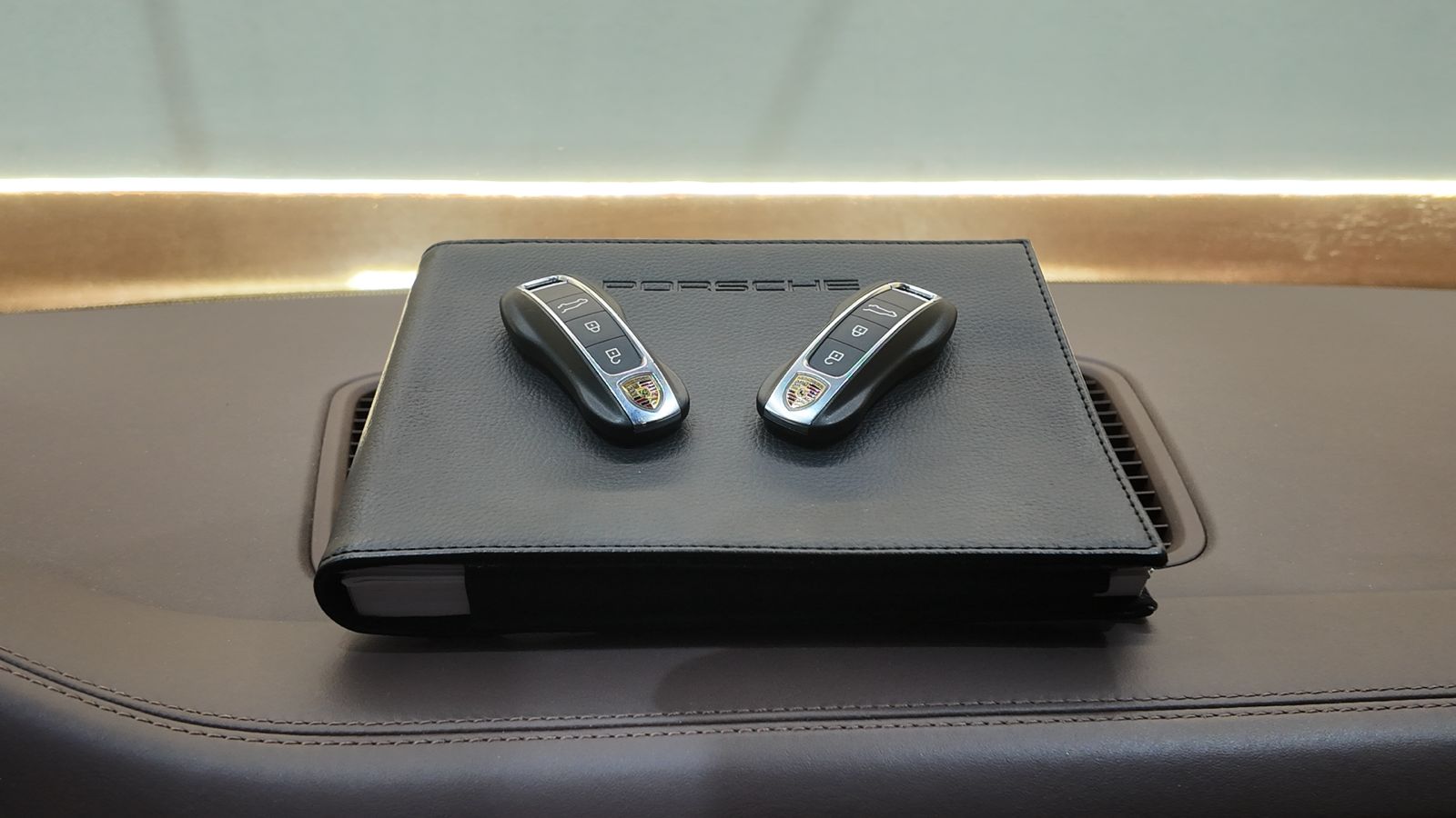 Dos llaves de Porsche sobre una carpeta de cuero negro en el interior de un vehículo